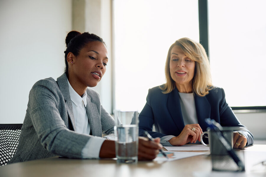 Two businesswomen cooperating while analyzing on reports in the office.